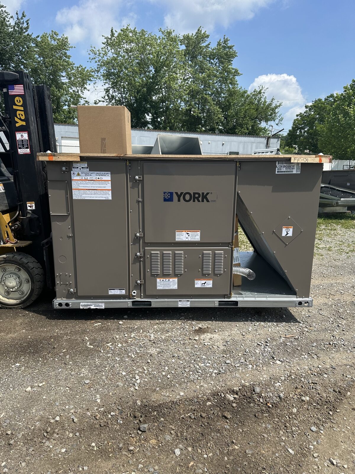 Brand-new York rooftop packaged unit staged on a forklift at ground level