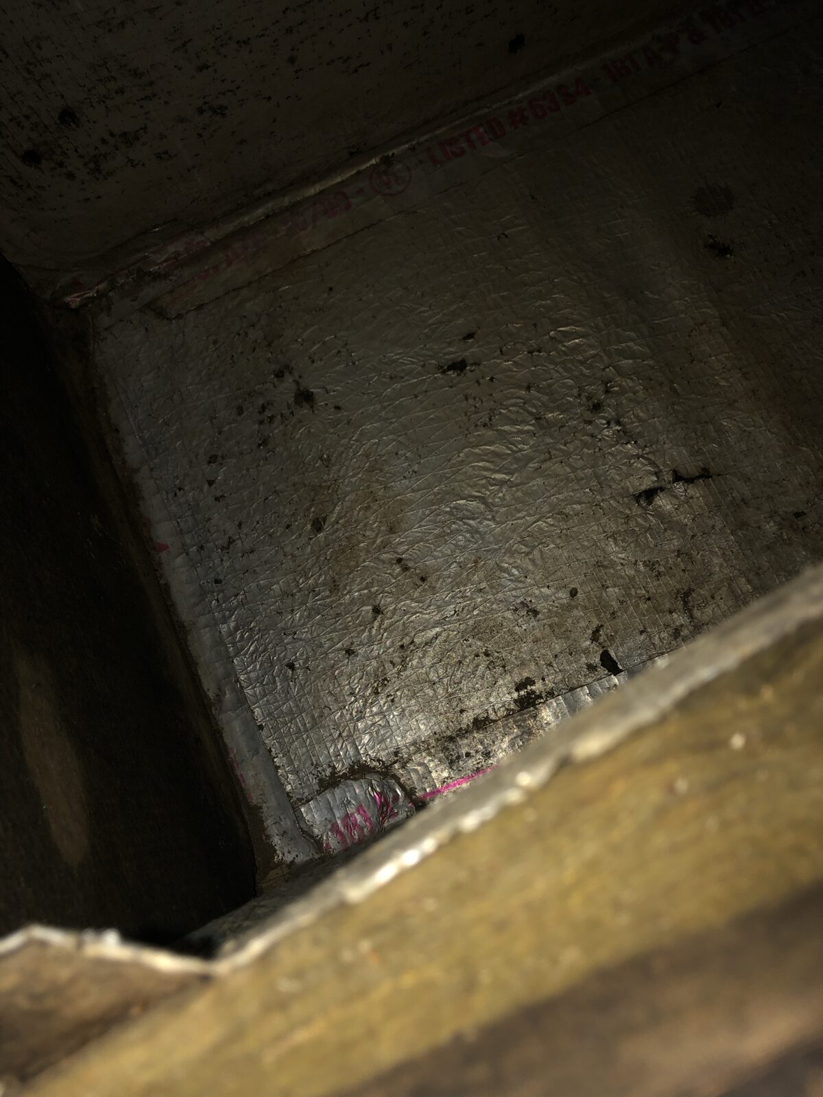 Heavily soiled interior of an HVAC return plenum thick with dust buildup